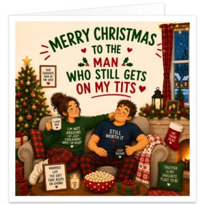 Funny Husband Christmas card featuring a cosy illustrated married couple relaxing on a sofa beside a decorated tree and fireplace. Bold text reads “Merry Christmas to the Man Who Still Gets on My T**s”. Humorous details include “Still Worth It” T-shirt, “I Love Him” and “Lucky B*****d” mugs, cheeky relationship signs, presents, stockings, fairy lights and snowy window scene.