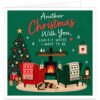 Romantic Christmas card for wife, girlfriend or partner with the message “Another Christmas With You. Exactly Where I Want to Be.” Cosy festive illustration features two armchairs beside a glowing log burner and decorated Christmas tree, with presents, steaming mugs, candles, lantern, holly, hearts and a sleeping dog. Warm green background with red festive details creates a loving Christmas scene for couples.
