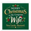 Funny rude Christmas card for wife from husband with the message “Merry Christmas to My Gorgeous Wife. You Lucky Bastard.” Elegant deep green background with cream, white and gold typography, large script Wife lettering topped with a red Santa hat, festive holly, red berries, gold flourishes and a small heart. Cheeky adult humour wife Christmas card with a stylish romantic festive design.