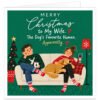 Funny Christmas card for wife from husband featuring the text “Merry Christmas to My Wife. The Dog’s Favourite Human. Apparently.” Cosy illustration of a married couple sitting on a cream sofa beside a decorated Christmas tree. Their golden-coloured dog lies happily across the wife’s lap while the husband looks unimpressed. The wife holds red wine and the husband a festive mug, with Christmas jumpers, patterned socks and a rich green background.