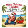 Funny Grandad Christmas card featuring the message "Merry Christmas Grandad. Still Sleighing It… Just a Bit Slower These Days!" Colourful illustration of an elderly Santa Claus wearing sunglasses, a red Hawaiian shirt, shorts and Santa hat, riding a blue mobility scooter along a tropical beach. He gives a thumbs-up while towing a miniature red sleigh filled with Christmas presents. Palm trees, golden sand and turquoise sea complete this humorous festive design on a white background.